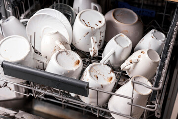 Unwashed, dirty dishes in dishwasher. Mess in the kitchen. Dirty kitchenware, plates and mugs....