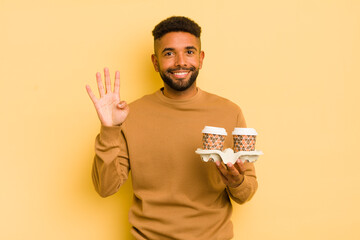 black afro man smiling and looking friendly, showing number four. take away coffee concept