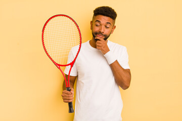 black afro man smiling with a happy, confident expression with hand on chin. tennis concept