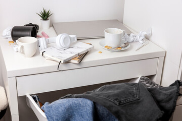Messy table with laptop, dirty cups, and stationary items. Cluttered workplace, desk. Concept of...