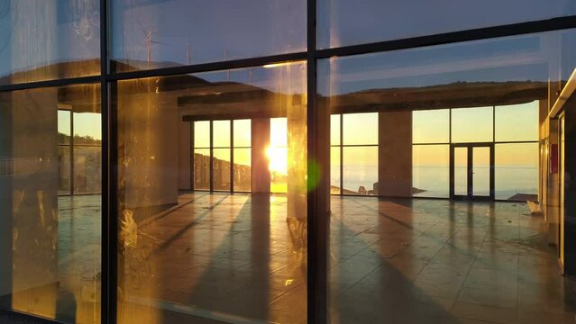 Retail space for lease. Interior of an office or business property for rent or sale. Setting sun shining through windows of an empty floor of real estate, sky reflecting in the glass.