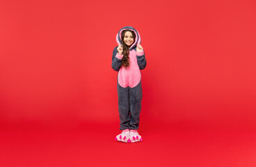 cheerful kid in comfortable pajama on red background, full length, home