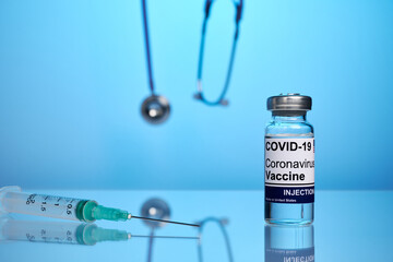 Covid vaccine vial and syringe - labs photo with blue background. Covid-19 treatment vial on a...