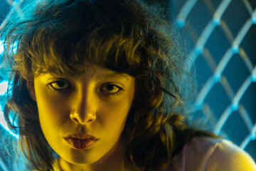 Portrait of a beautiful young woman with curly hair in neon lighting.