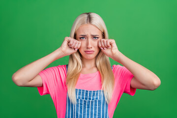 Photo of stressed offended cute lady cry wipe tears look camera wear striped overall isolated green color background