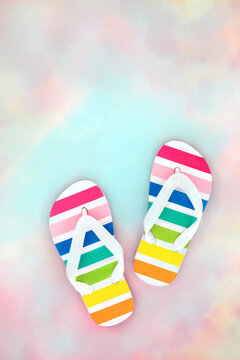Rainbow flip flops on pastel pink blue sky cloud background. Travel, tourism, vacation, fun and LGBT concept. Copy space.
