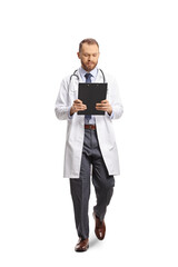 Full length portrait of a young male doctor reading a document and walking towards camera