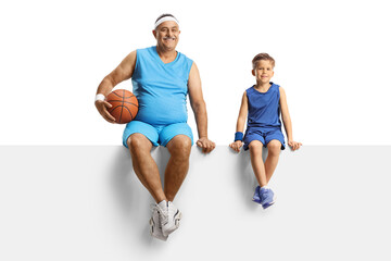 Obraz na płótnie Canvas Mature man with a basketball and a boy in sport jersey sitting on a blank panel