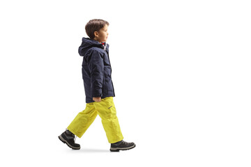 Full length profile shot of a boy in winter clothes walking