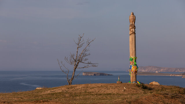 Ein Totem Pfahl steht auf einem H&uuml;gel des Schamanenfelsens bei Chuschir auf Olchon hoch &uuml;ber einer Bucht des Baikalsees mit seinem blauen Wasser.