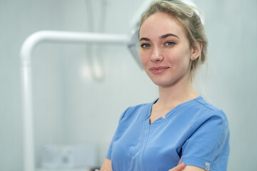 Dentist assistant or female dentist in dentistry room. Portrait of female doctor wearing a blue uniform. Pretty nurse is looking at camera with smile. Copy space