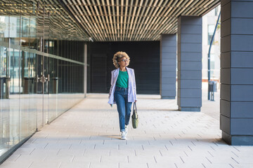 Confident black business woman walking in office district smiling empowered African American female executive enjoying successful corporate career
