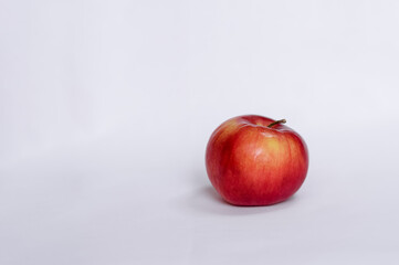 A whole red apple on a white tablecloth. Side view