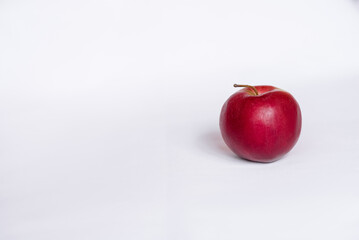 A whole red apple on a white tablecloth. Side view