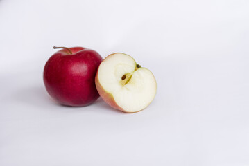 A whole red apple and a sliced red apple on a white tablecloth. Side view