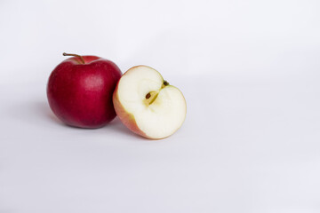 A whole red apple and a sliced red apple on a white tablecloth. Side view