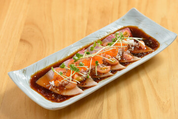 Fish Hamachi Carpaccio with chili sauce in a white tray on wooden background top view of japanese...