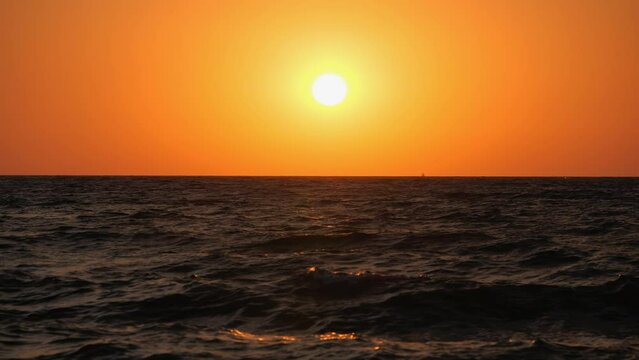 Sunset. The red sun sets over the horizon in a choppy sea.