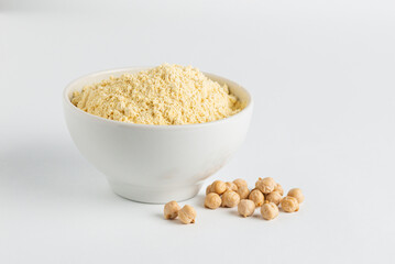 Chickpea flour in white ceramic bowl and chickpeas beans on a white background clouse up