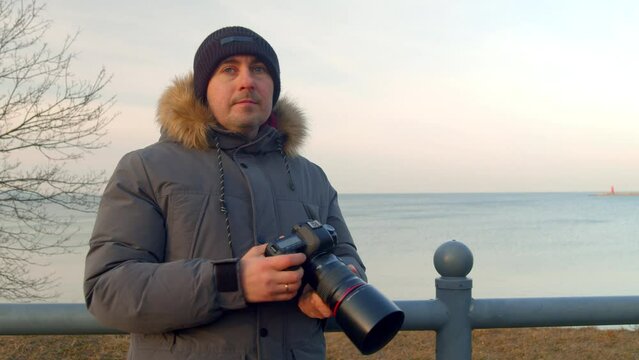 Professional male photographer takes pictures of the seascape with a SLR camera takes pictures of the picturesque landscape nature travel adventures.