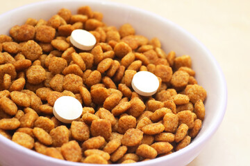 Cat food with three pills in a bowl on the floor. Vitamins for cats. Cat treatment