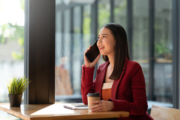 Asian businesswoman talking on the phone with customers at a coffee shop