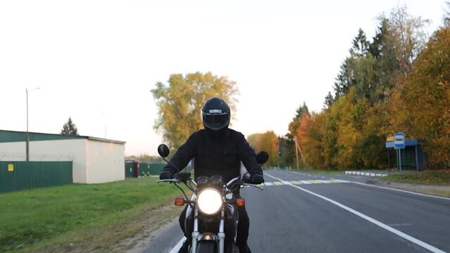 male biker motorcyclist rides on the road in warm clothes, riding a retro motorcycle on a journey.