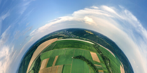 Aerial view from high altitude of little planet earth with green and yellow cultivated agricultural fields with growing crops on bright summer day © bilanol
