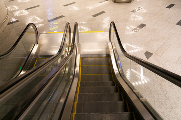 Fototapeta premium Top view of the escalator. Empty metro station. The escalator stairs lead down.