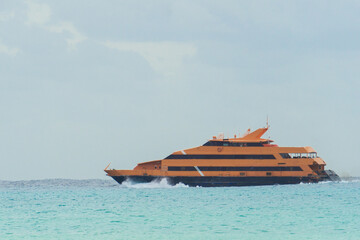 The liner sails on the sea against a cloudy sky. Orange yacht on the waves. Double deck ship.