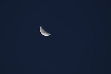 Obraz na płótnie Canvas La luna en su fase creciente en fondo azul marino