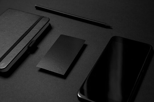 Mock up business template. Black blank business card stationery on black desktop with office supplies