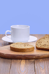 slices of rye bread with seeds and a white mug with a saucer on a wooden board