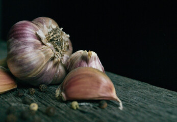 garlic and garlic cloves on a black background on a wooden board