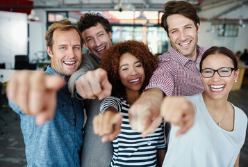 Our team wants you. Portrait of a group of smiling coworkers pointing at the camera while standing...