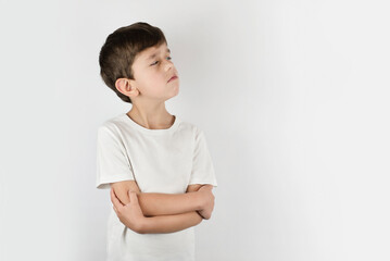 A little boy on a light background took offense at someone and looks away, the boy is sad and...