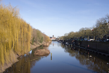 Canal in the center of 's-Hertogenbosch with trees on the side in the Netherlands with a clear blue sky