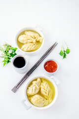 Dumplings are served in white cups with sauces on a serving board . Top view. Copy space
