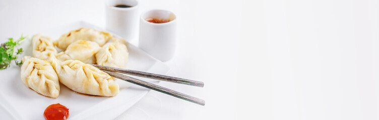 Steamed dumplings and soy sauce. asian dumplings Gyoza potstickers in white ceramic plate served with chopsticks over linen table cloth. Asian dinner.