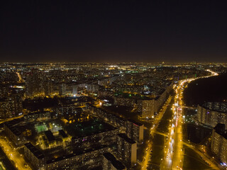 Obraz premium Birds-eye view of residential district and motorway in the night. Buildings and bright illuminated streets. Aerial view