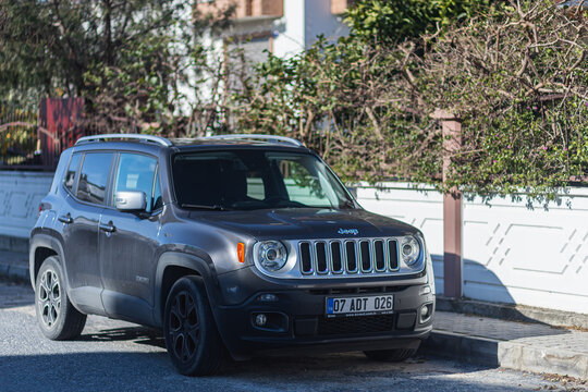 Side, Turkey -January 27, 2022: black Jeep Renegade   is parking  on the street on a  summer day against the backdrop of a  building,  fence, park