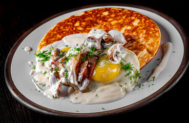 pancake with mushroom sauce, bacon and egg on plate
