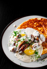 pancake with mushroom sauce, bacon and egg on plate