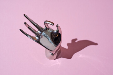 iron Hand-shaped jewelry holder with shadow on a trendy pink background. OK hand shape ring display holder for jewelry display