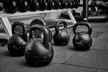 Plakat Dumbbells and kettlebells on a floor. Bodybuilding equipment. Fitness or bodybuilding concept background. black and white photography