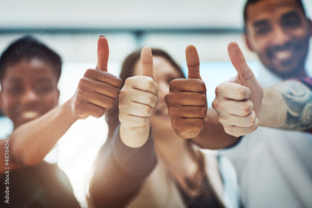 Poster Go get that success. Cropped shot of a team of colleagues showing thumbs up at work.