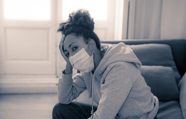 Lonely african american young woman with face mask suffering from depression at home in isolation