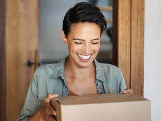 Right on time. Shot of a smiling young woman standing at her front door receiving a package from a...