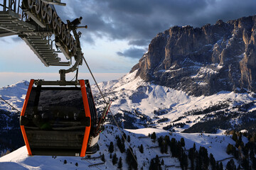 High alpine peaks covered in snow in the afternoon light with slightly out of focus cable car in...