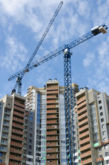 Fototapeta na wymiar Blue construction cranes against the spring blue sky.